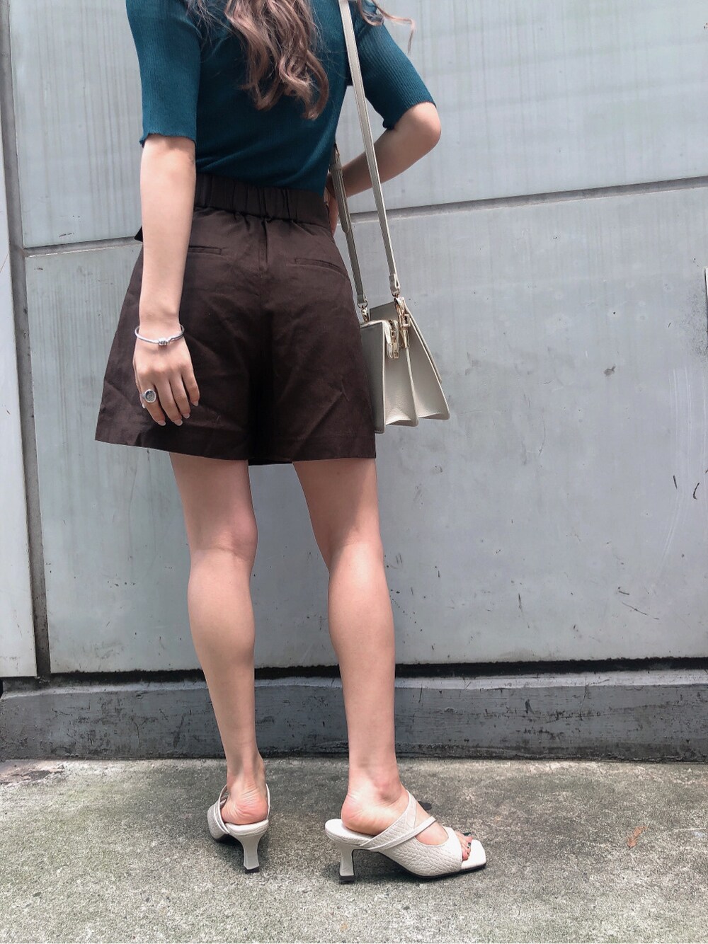 ホワイト系のハンドバッグ、ホワイト系のサンダル、グリーン系のニット/セーターを着用したレディースの夏コーディネートの5枚目の写真