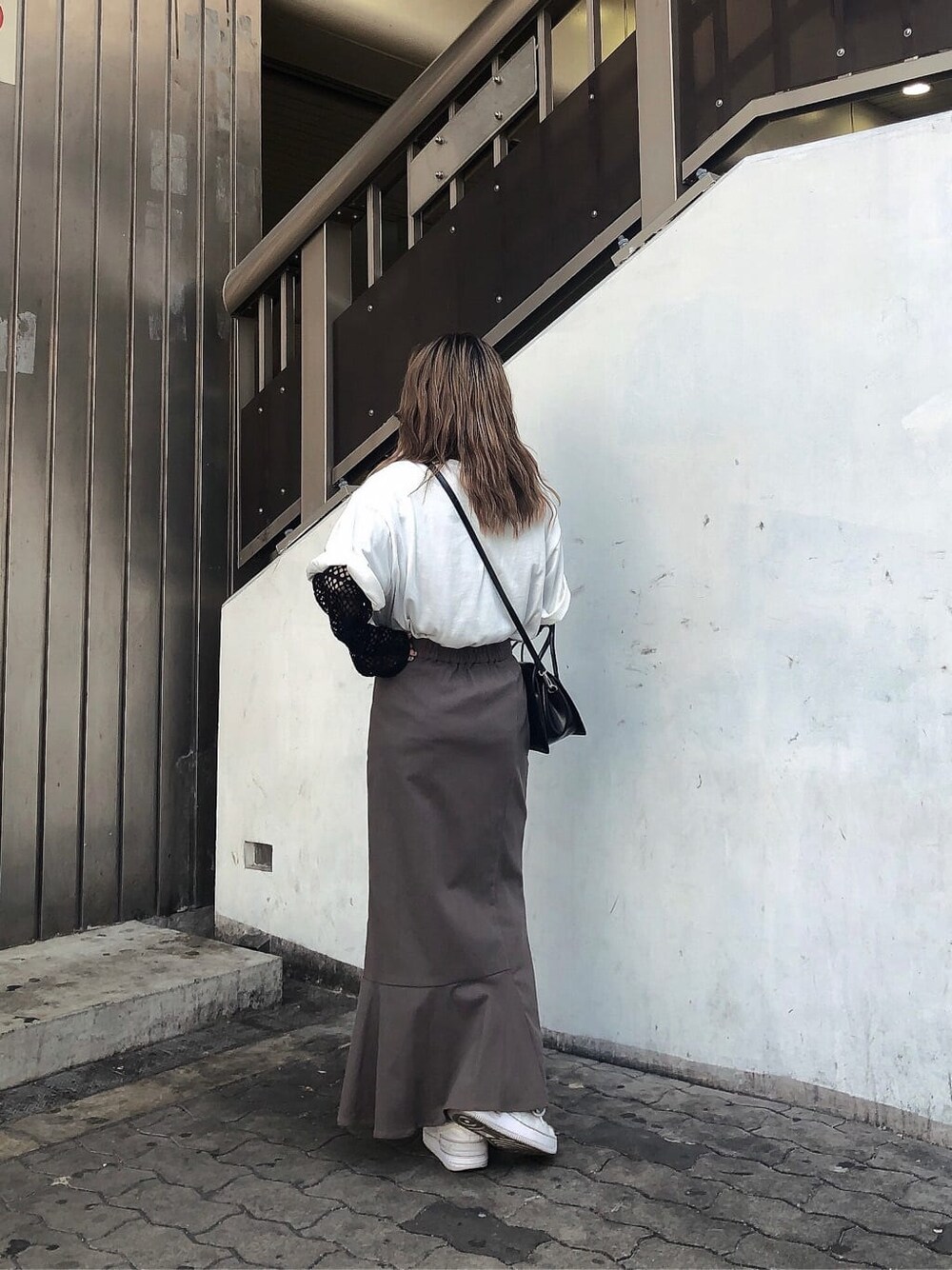 グレー系のスカート、ブラック系のハンドバッグ、ホワイト系のTシャツ/カットソーを着用したレディースの春コーディネートの2枚目の写真