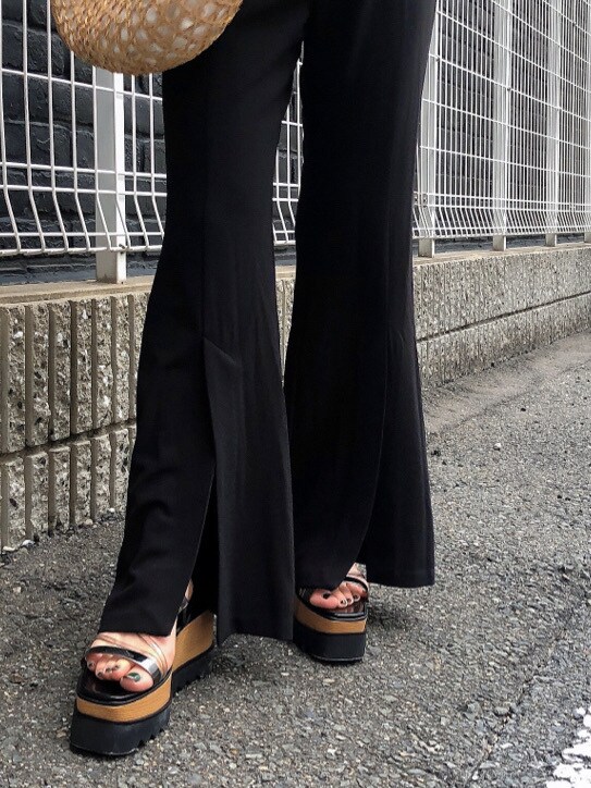 ブラック系のスラックス、ベージュ系のかごバッグ、ブラック系のサンダルを着用したレディースの夏コーディネートの6枚目の写真