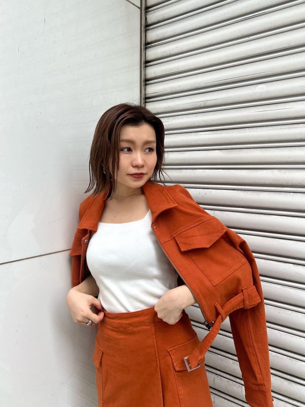 ホワイト系のニット/セーター、オレンジ系のデニムジャケット、オレンジ系のスカートを着用したレディースの夏コーディネートの5枚目の写真