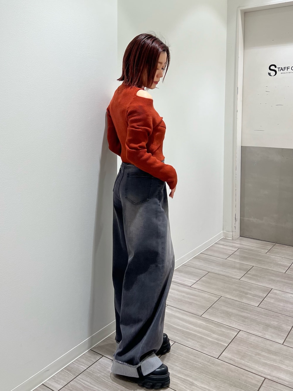 オレンジ系のニット/セーター、グレー系のデニムパンツを着用したレディースの冬コーディネートの2枚目の写真