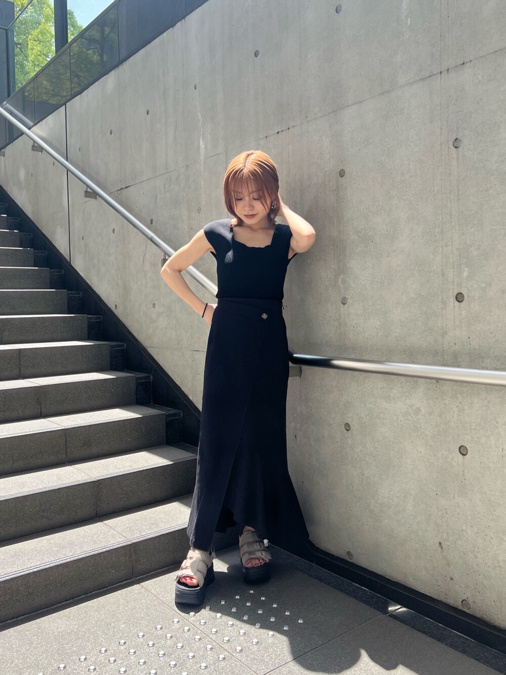 ブラック系のスカート、ブラック系のタンクトップ、ブラウン系のサンダルを着用したレディースの春コーディネートの2枚目の写真