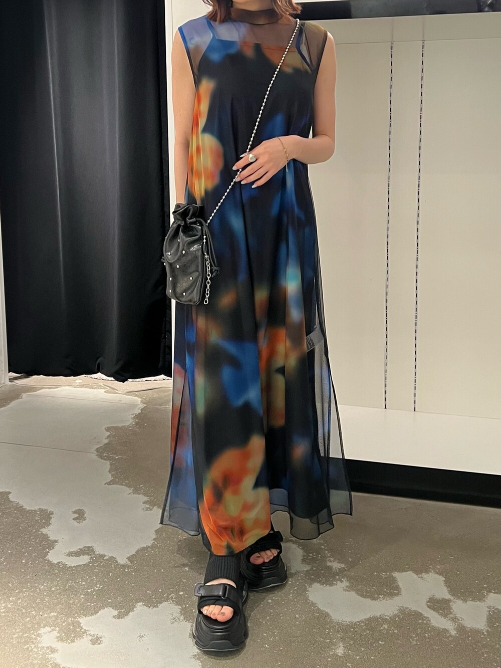 ブラック系のワンピース、ブラック系のサンダル、ブラック系のショルダーバッグを着用したレディースの春コーディネートの5枚目の写真