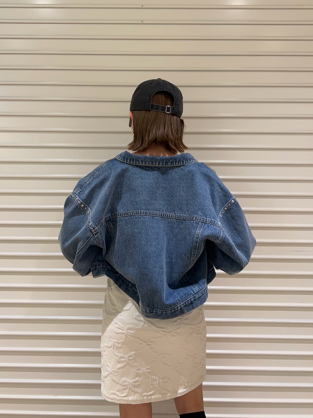 ブルー系のデニムジャケット、ホワイト系のワンピース、ブラック系のキャップを着用したレディースの春コーディネートの5枚目の写真