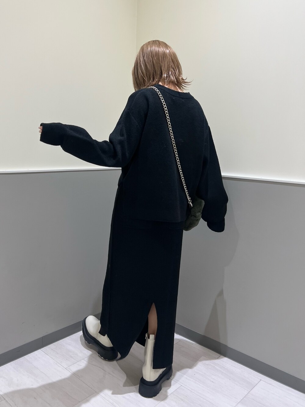ブラック系のニット/セーター、ブラック系のスカート、ホワイト系のブーツを着用したレディースの冬コーディネートの4枚目の写真