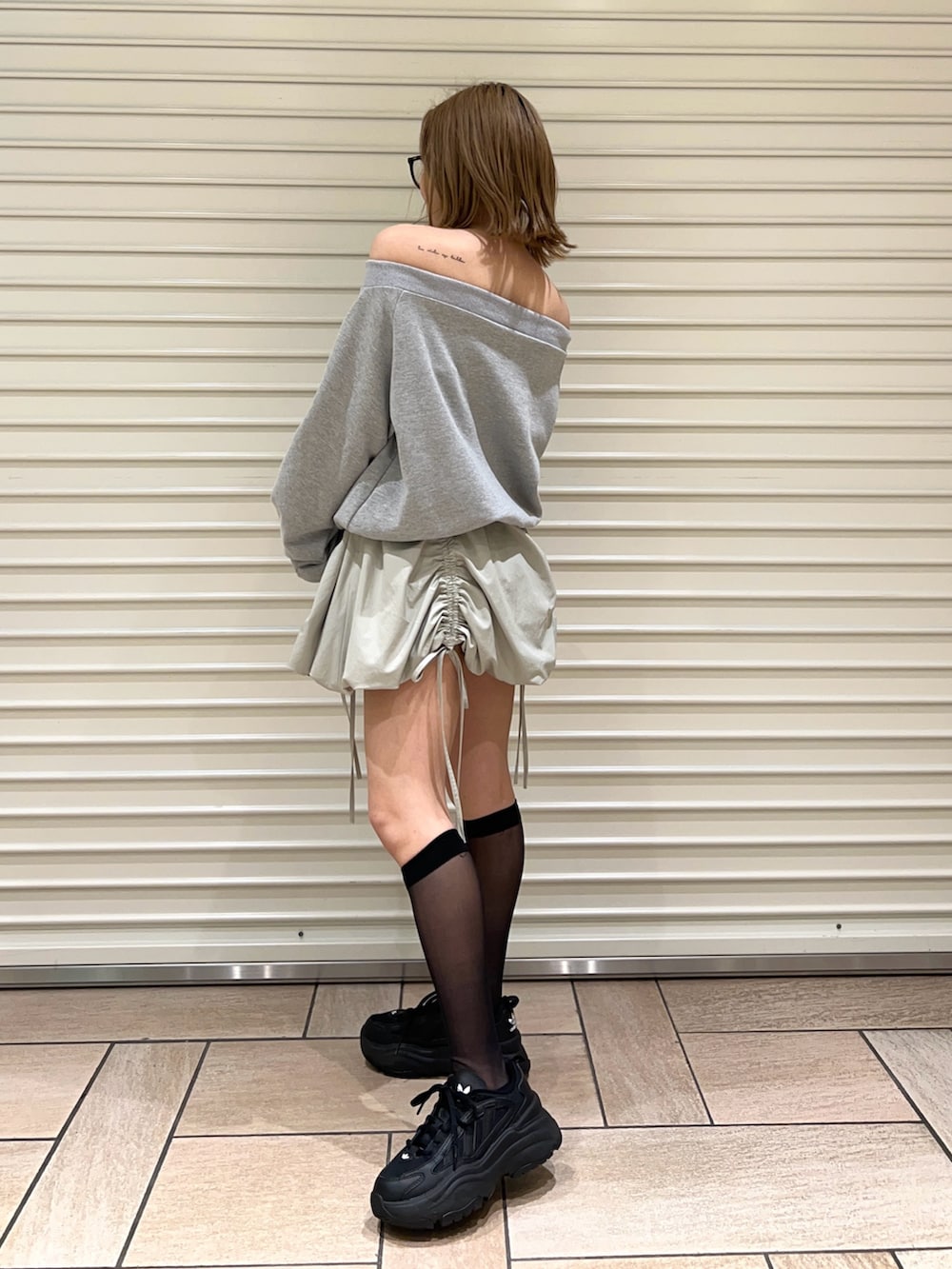 グリーン系のスカート、グレー系のスウェットを着用したレディースの春コーディネートの2枚目の写真