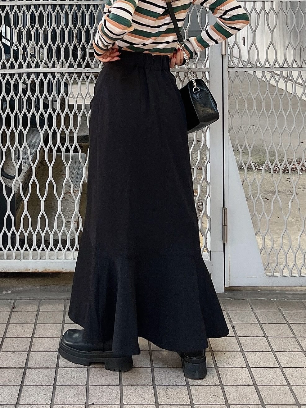 ブラック系のブーツ、ブラック系のショルダーバッグ、ブラック系のスカートを着用したレディースの秋コーディネートの8枚目の写真