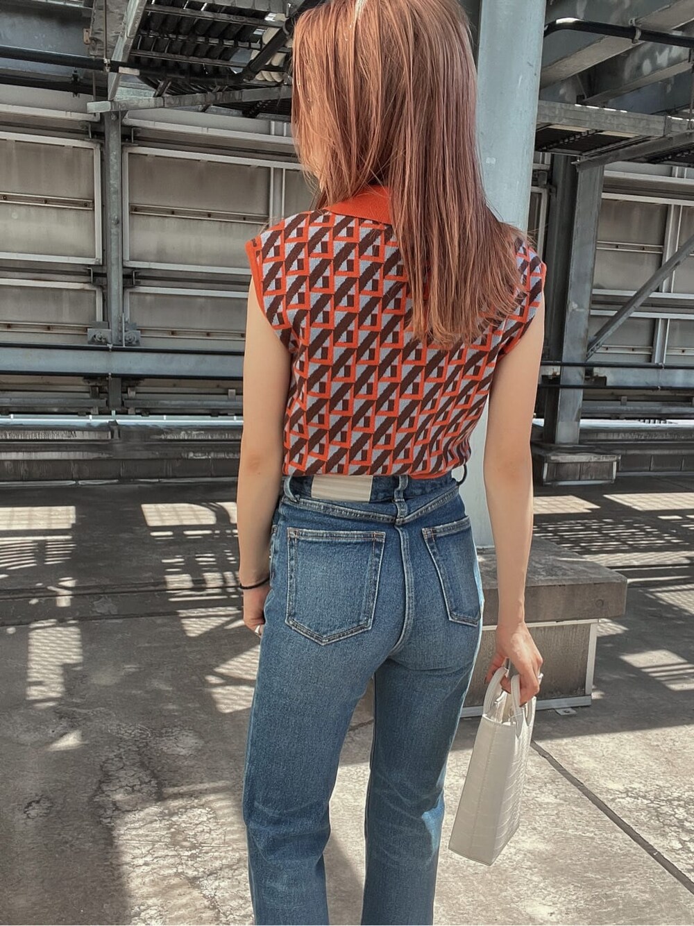 ブルー系のデニムパンツ、オレンジ系のニット/セーター、ホワイト系のブーツを着用したレディースの夏コーディネートの7枚目の写真