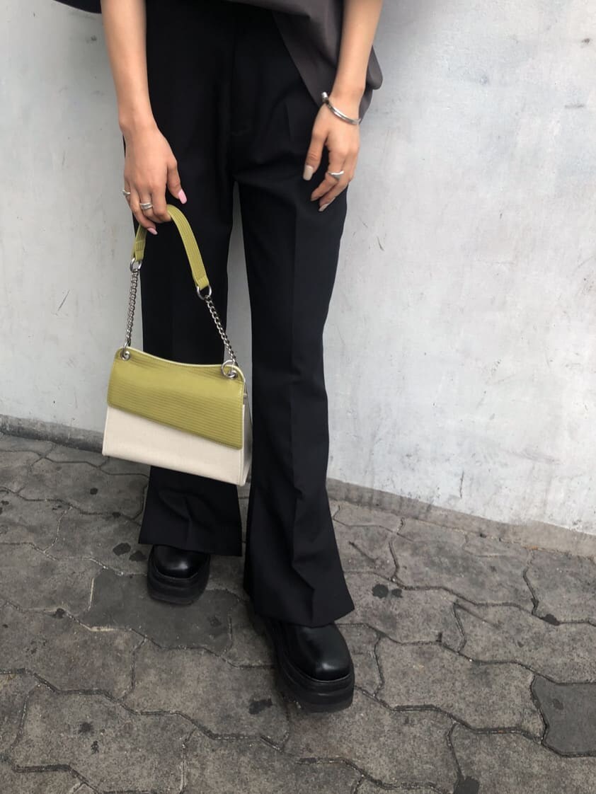 ブラック系のスラックス、ホワイト系のハンドバッグ、グレー系のTシャツ/カットソーを着用したレディースの春コーディネートの7枚目の写真