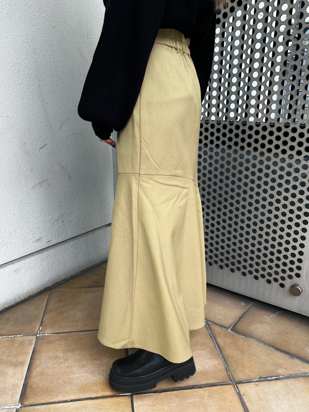 グリーン系のスカート、ブラック系のニット/セーター、ブラック系のショルダーバッグを着用したレディースの冬コーディネートの8枚目の写真