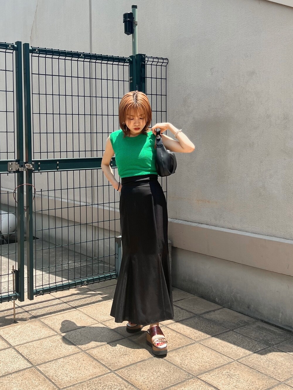 グリーン系のタンクトップ、ブラック系のスカート、その他のサンダルを着用したレディースの夏コーディネートの3枚目の写真
