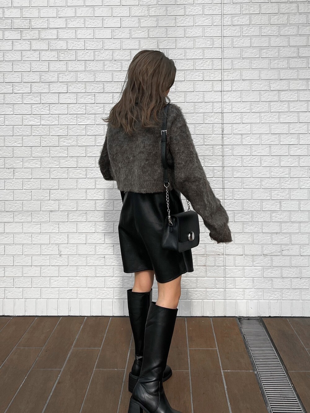 ブラック系のワンピース、ブラック系のブーツ、ブラウン系のニット/セーターを着用したレディースの秋コーディネートの4枚目の写真