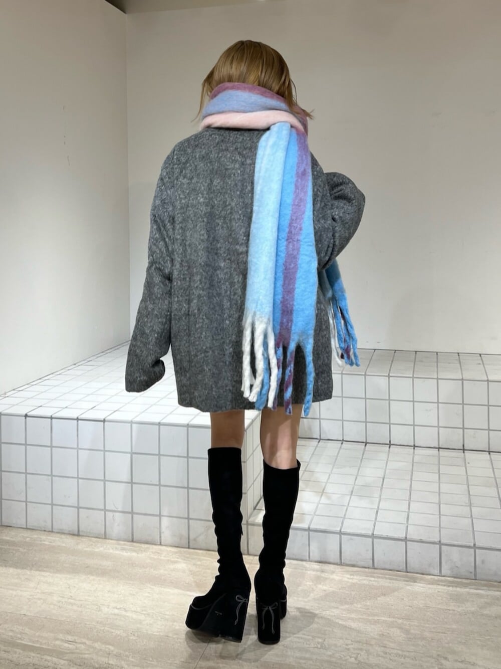 ブラック系のブーツ、グレー系のテーラードジャケット、その他のマフラーを着用したレディースの冬コーディネートの2枚目の写真