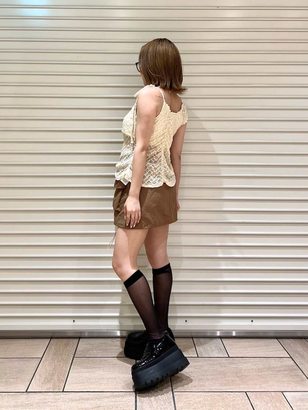 ブラウン系のスカート、ホワイト系のタンクトップを着用したレディースの夏コーディネートの2枚目の写真