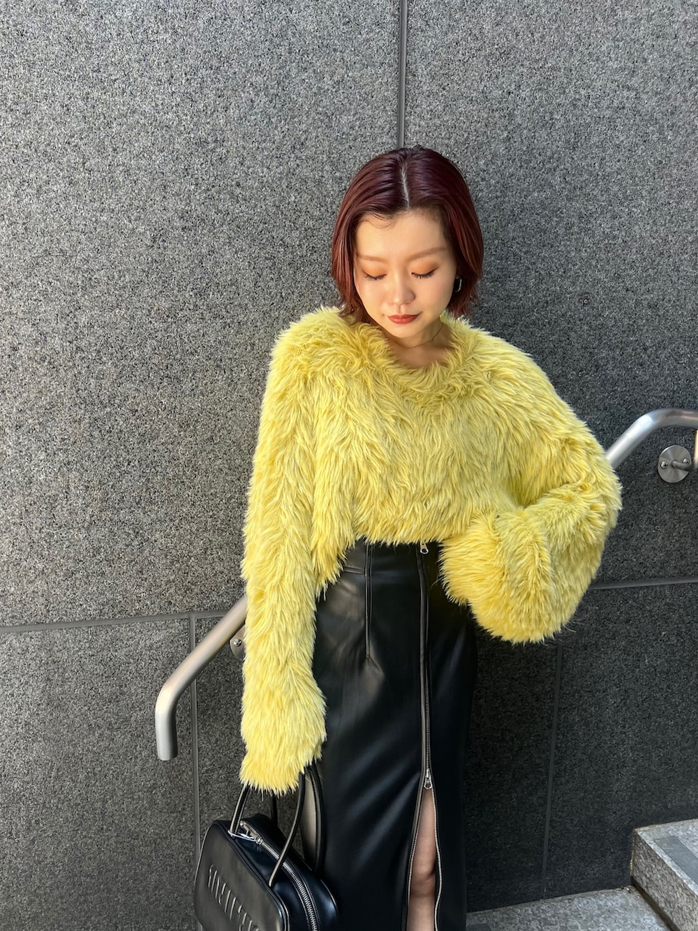 イエロー系のニット/セーター、ブラック系のスカート、ブラック系のブーツを着用したレディースの秋コーディネートの5枚目の写真