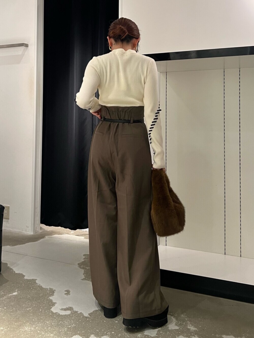 ホワイト系のニット/セーター、ブラック系のブーツ、ブラウン系のハンドバッグを着用したレディースの秋コーディネートの3枚目の写真