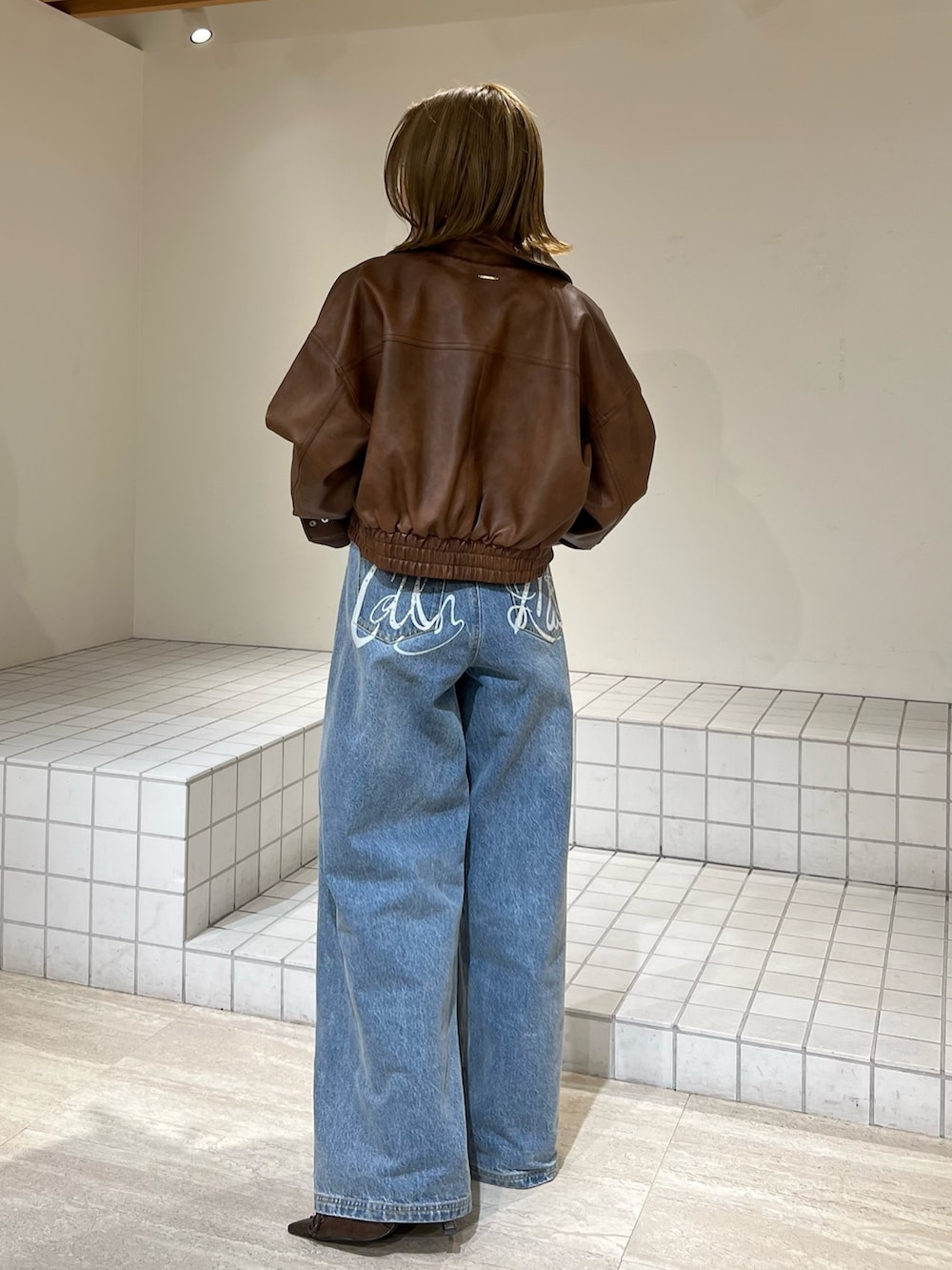 イエロー系のTシャツ/カットソー、ブルー系のその他パンツ、ブラウン系のブルゾンを着用したレディースの冬コーディネートの3枚目の写真