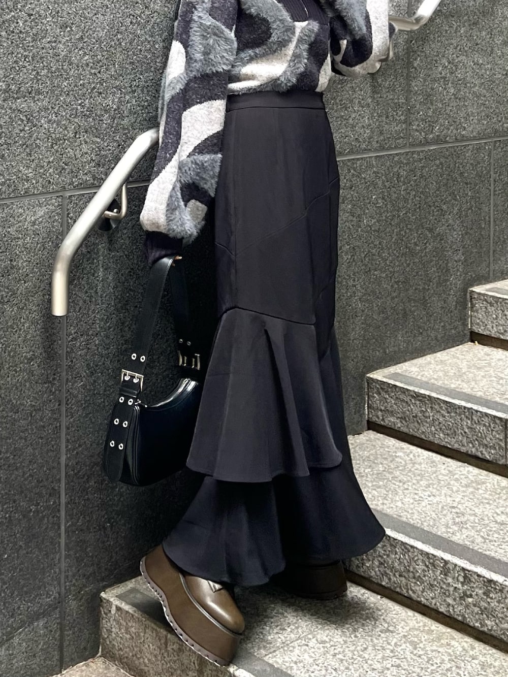 ブラック系のニット/セーター、ブラウン系のブーツ、ブラック系のスカートを着用したレディースの秋コーディネートの7枚目の写真