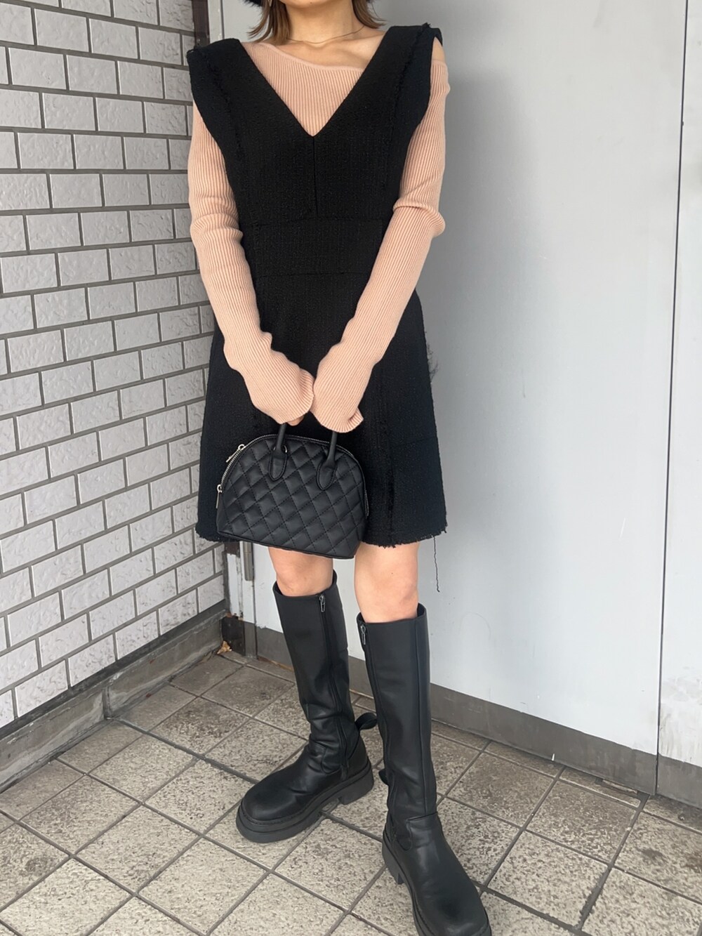 ベージュ系のニット/セーター、ブラック系のワンピース、ブラック系のブーツを着用したレディースの冬コーディネートの7枚目の写真