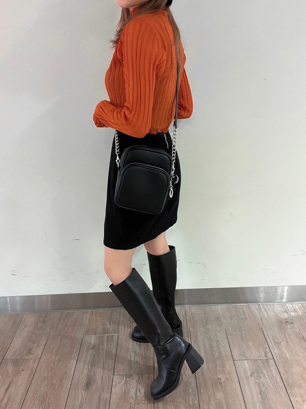 ブラック系のブーツ、オレンジ系のニット/セーター、ブラック系のスカートを着用したレディースの秋コーディネートの8枚目の写真