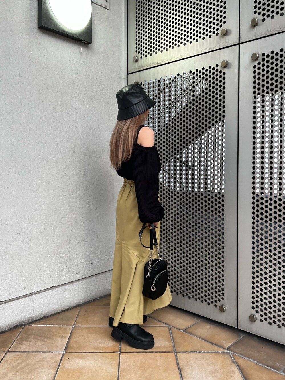 グリーン系のスカート、ブラック系のニット/セーター、ブラック系のショルダーバッグを着用したレディースの冬コーディネートの2枚目の写真