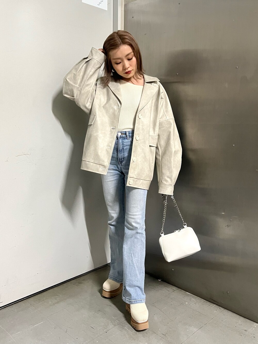 ホワイト系のブルゾン、ホワイト系のニット/セーター、ホワイト系のハンドバッグを着用したレディースの冬コーディネートの3枚目の写真