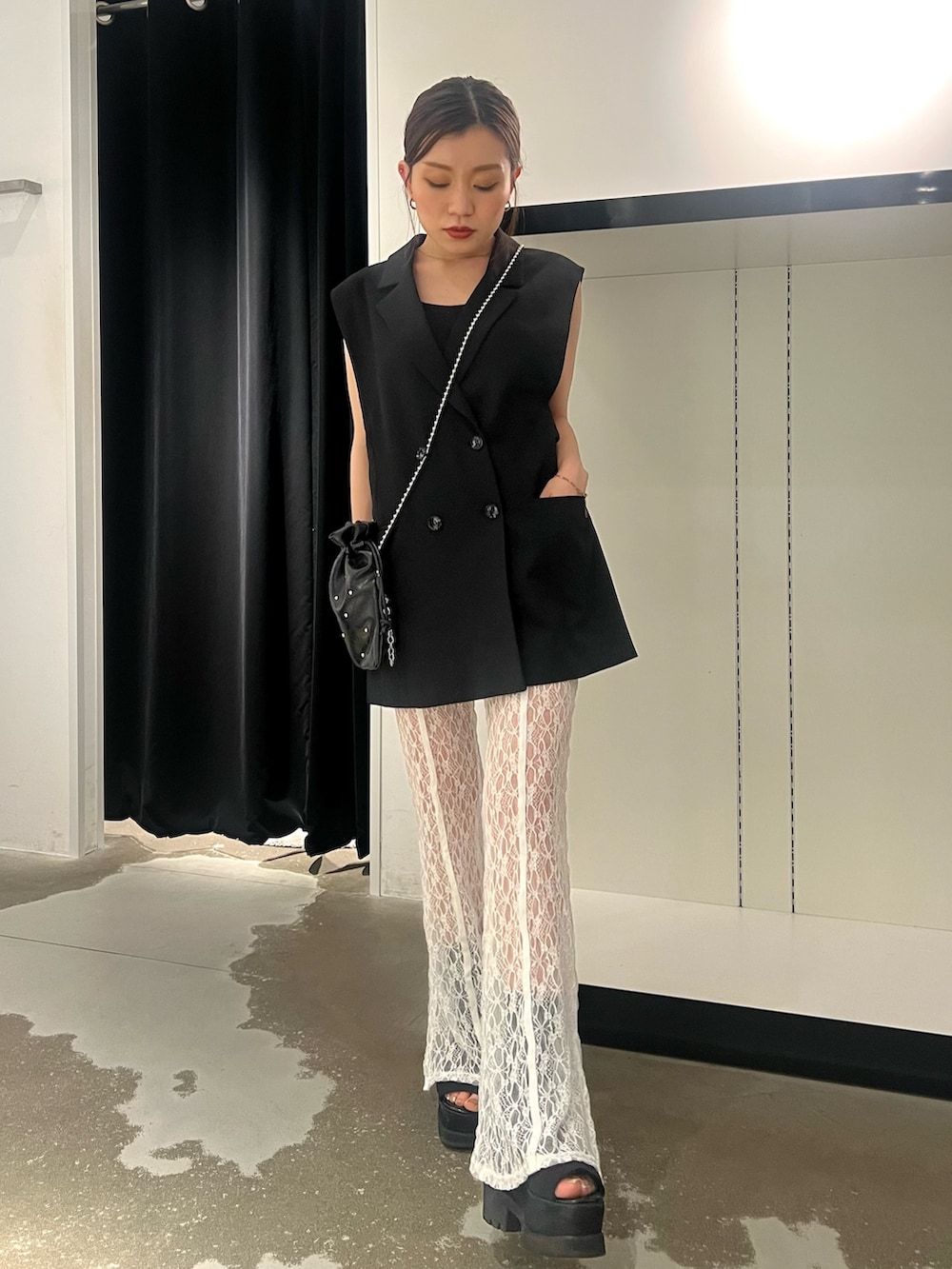 ブラック系のベスト、ホワイト系のその他パンツ、ブラック系のサンダルを着用したレディースの春コーディネートの3枚目の写真