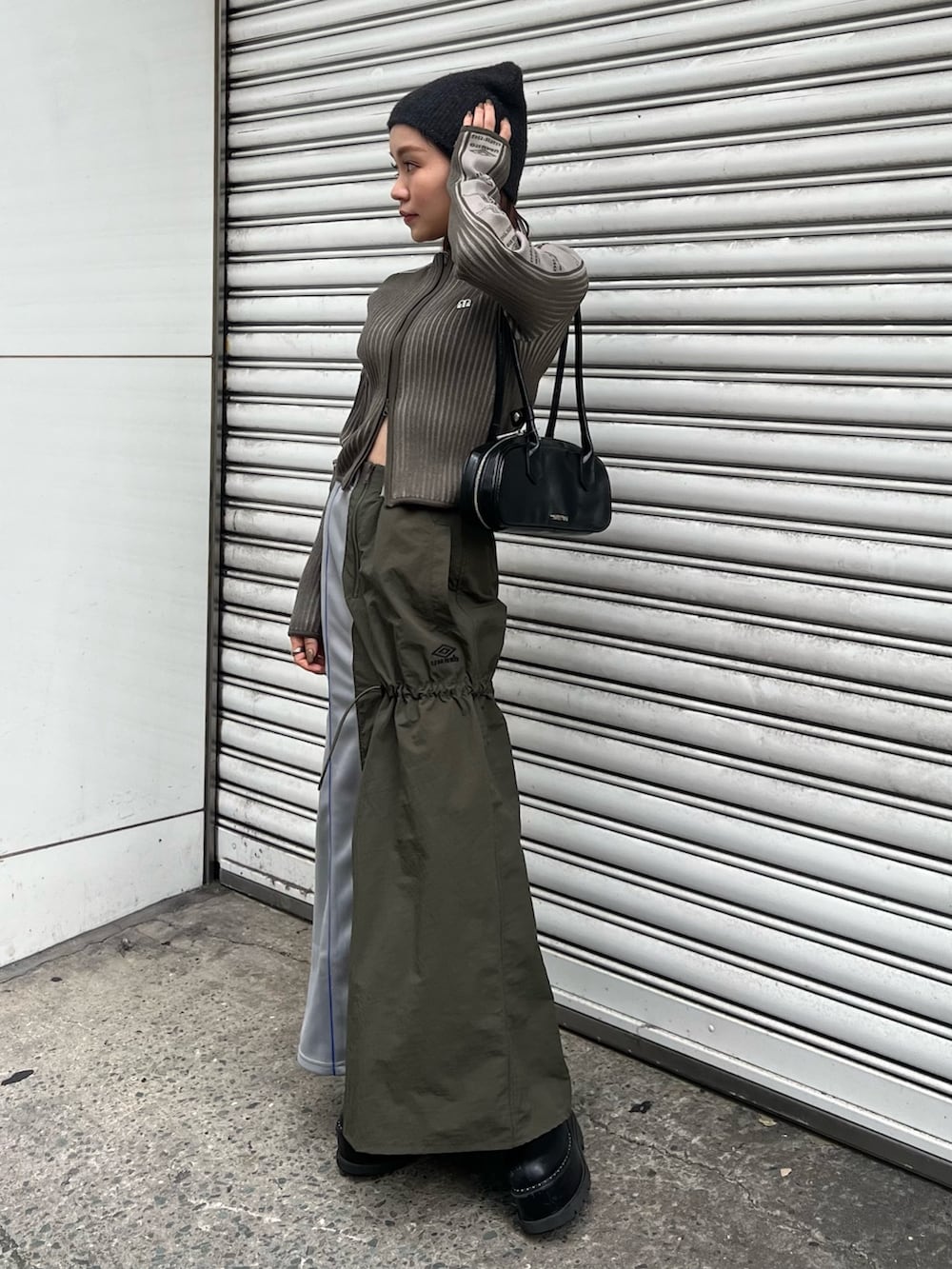 ブラック系のブーツ、グリーン系のニット/セーター、グリーン系のスカートを着用したレディースの秋コーディネートの2枚目の写真