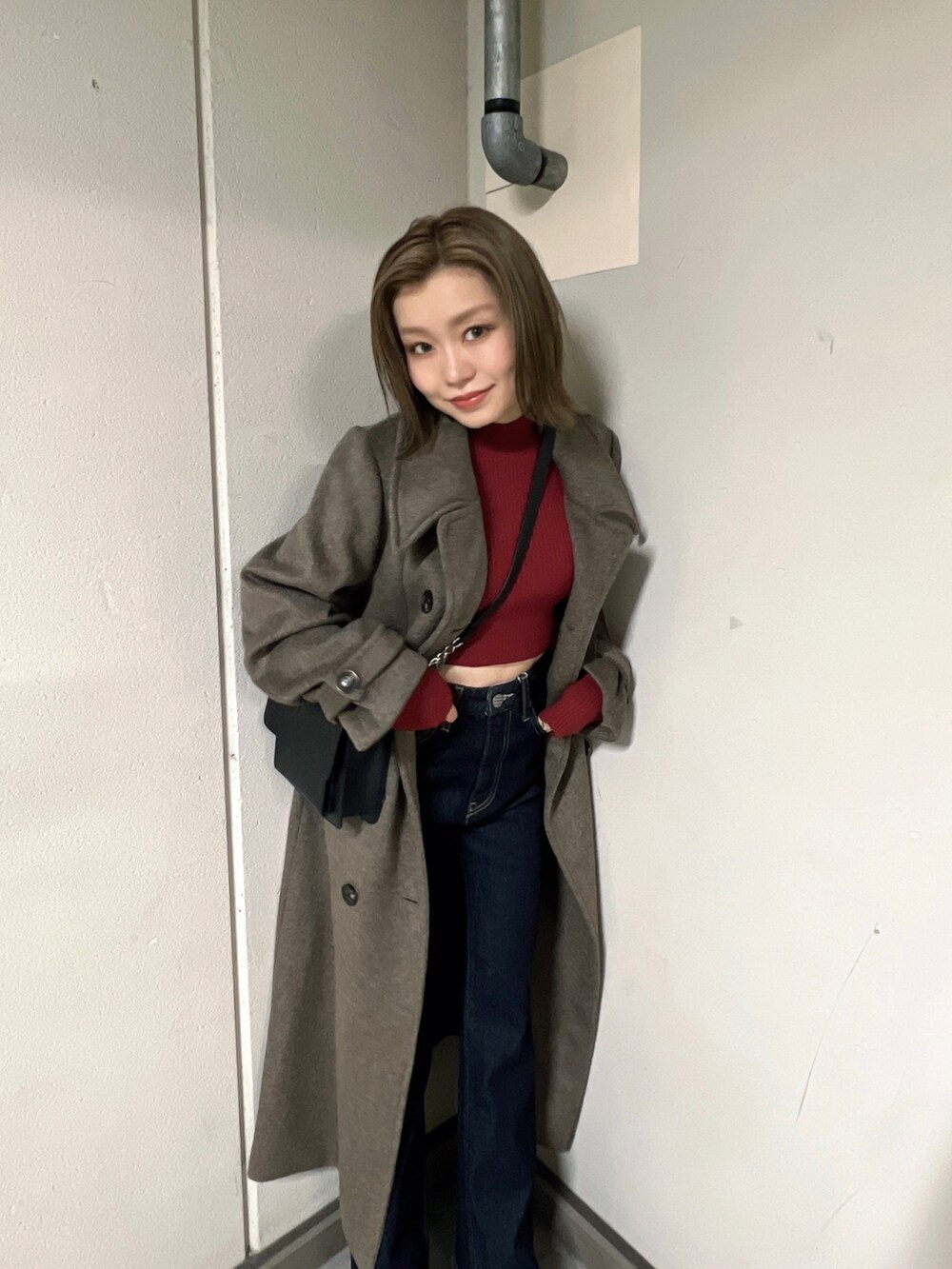 ブルー系のデニムパンツ、ブラウン系のチェスターコート、レッド系のニット/セーターを着用したレディースの秋コーディネートの4枚目の写真