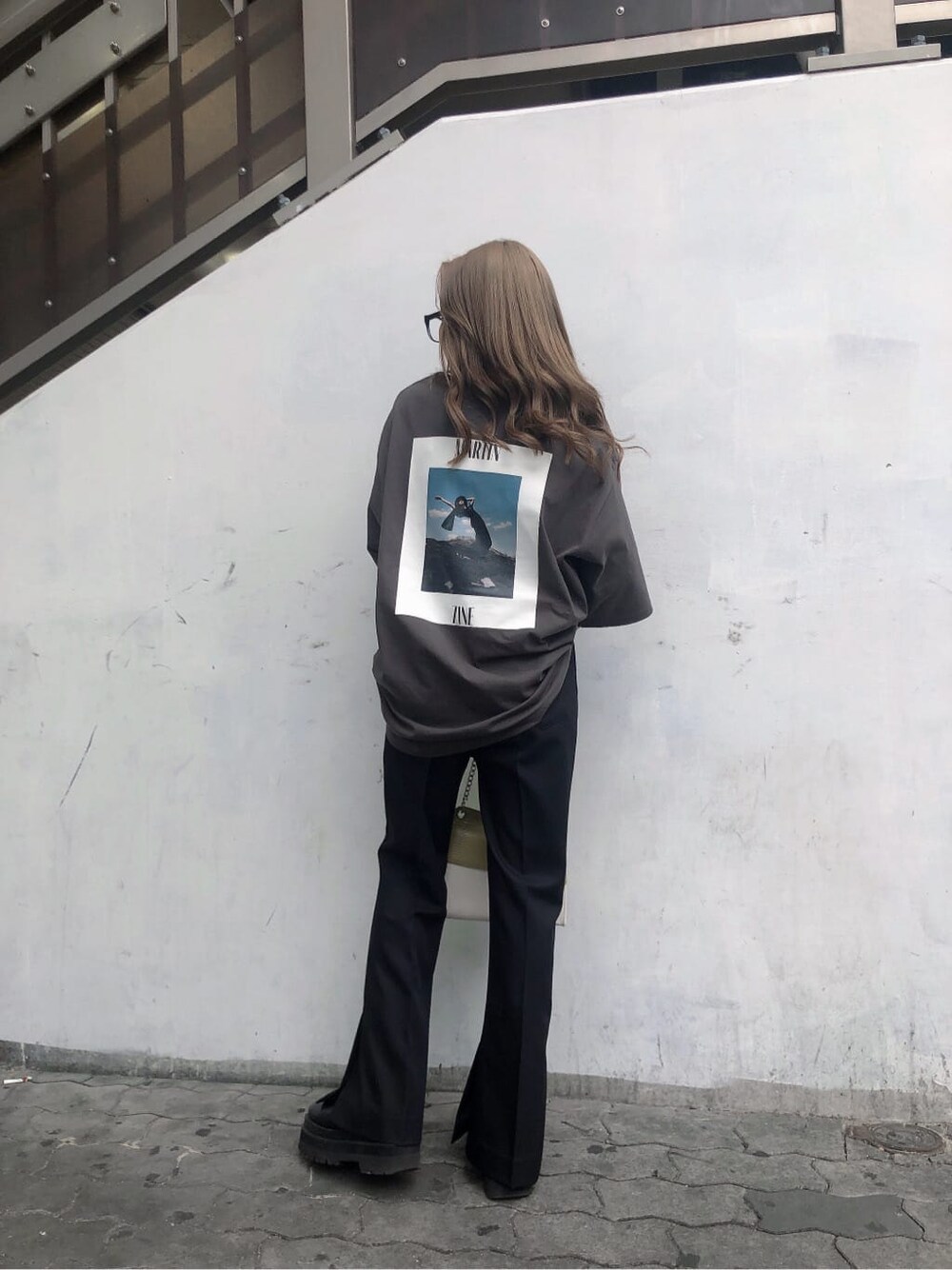 ブラック系のスラックス、ホワイト系のハンドバッグ、グレー系のTシャツ/カットソーを着用したレディースの春コーディネートの4枚目の写真