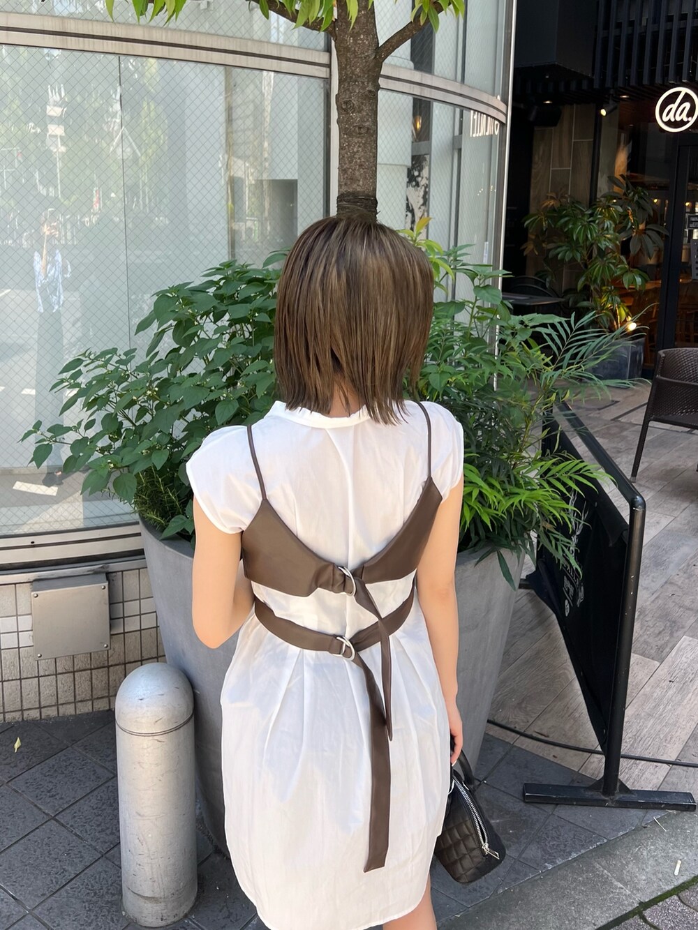 ブラウン系のワンピース、ブラック系のハンドバッグ、ブラック系のブーツを着用したレディースの春コーディネートの5枚目の写真