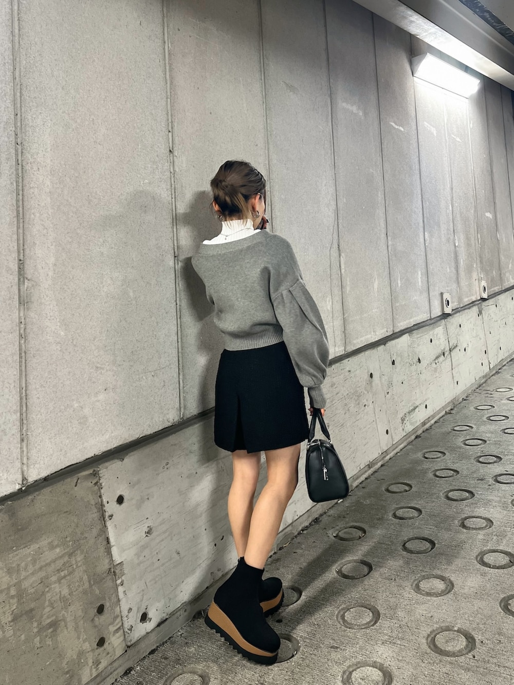 グレー系のカーディガン/ボレロ、ブラック系のブーツ、ホワイト系のニット/セーターを着用したレディースの冬コーディネートの2枚目の写真