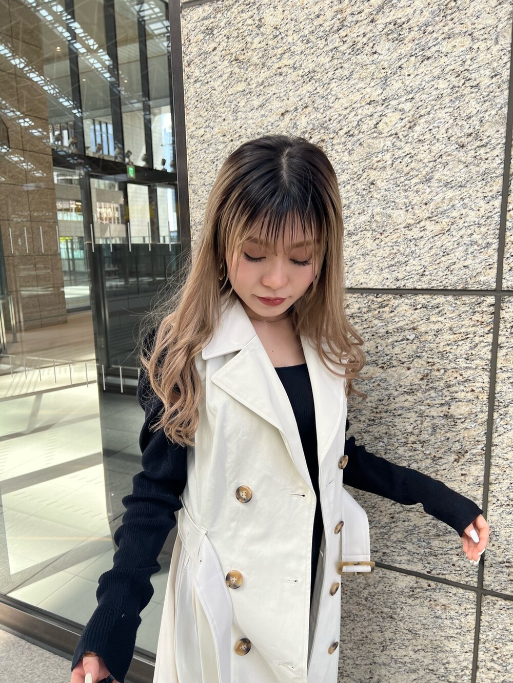 ホワイト系のトレンチコート、ブラック系のハンドバッグを着用したレディースの春コーディネートの5枚目の写真