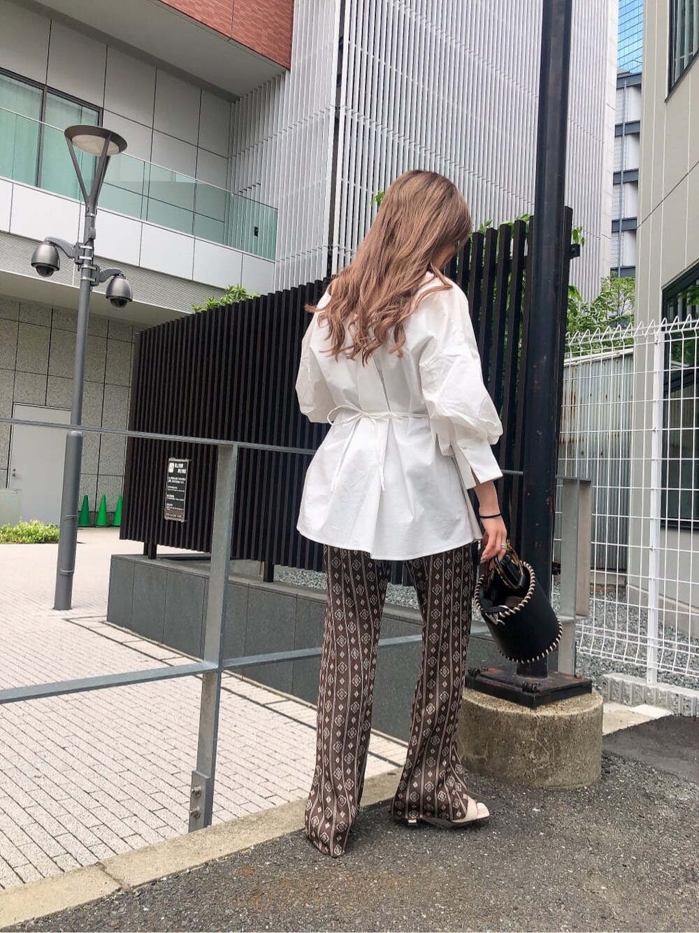 ブラック系のハンドバッグ、ホワイト系のシャツ/ブラウス、ブラウン系のその他パンツを着用したレディースの夏コーディネートの3枚目の写真