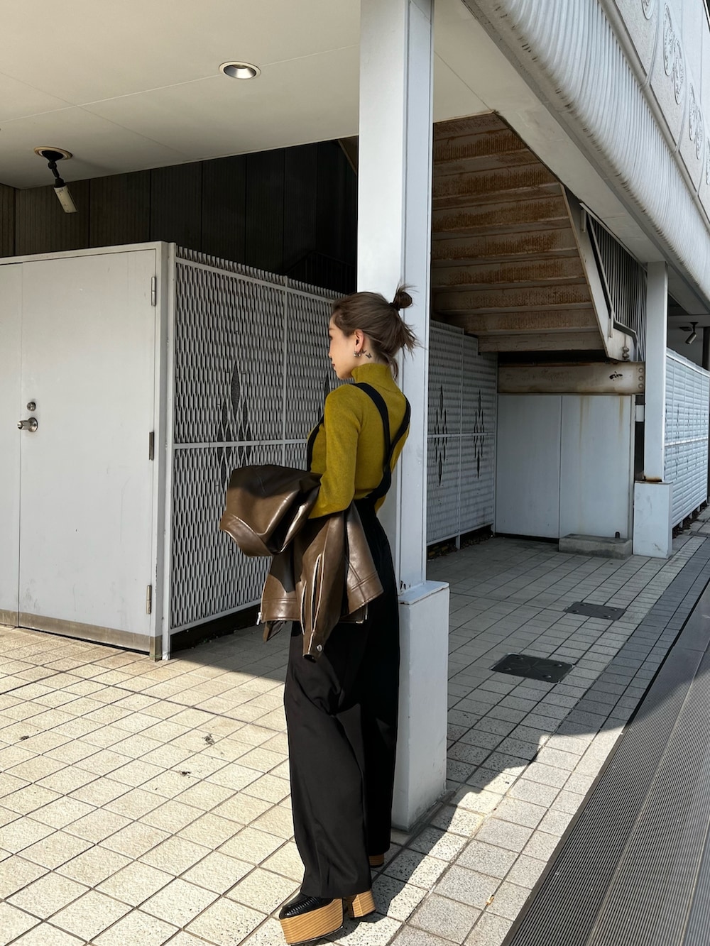 ブラウン系のライダースジャケット、ブラック系のスラックス、ブラック系のローファーを着用したレディースの秋コーディネートの6枚目の写真