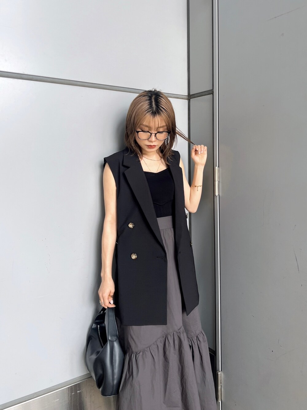 ブラック系のベスト、ブラック系のニット/セーター、グレー系のスカートを着用したレディースの夏コーディネートの5枚目の写真
