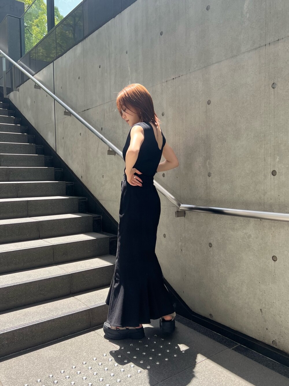 ブラック系のスカート、ブラック系のタンクトップ、ブラウン系のサンダルを着用したレディースの春コーディネートの4枚目の写真