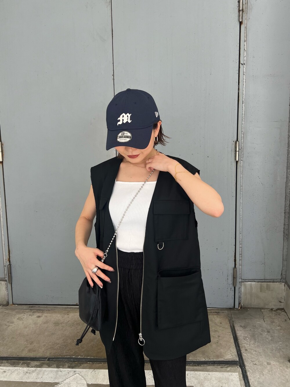 ブラック系のベスト、ホワイト系のニット/セーター、ブルー系のキャップを着用したレディースの夏コーディネートの6枚目の写真