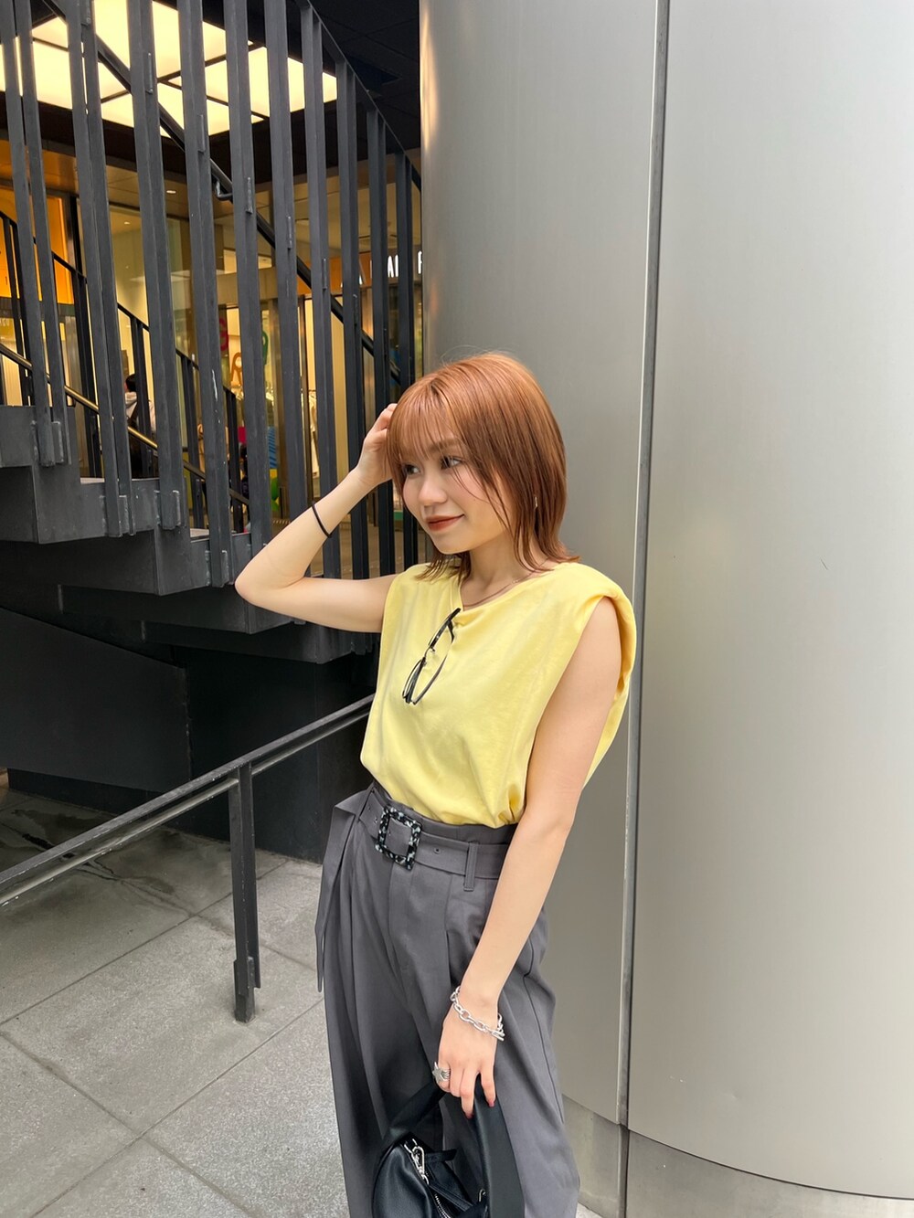 ブラック系のサンダル、グレー系のスラックス、イエロー系のTシャツ/カットソーを着用したレディースの春コーディネートの5枚目の写真