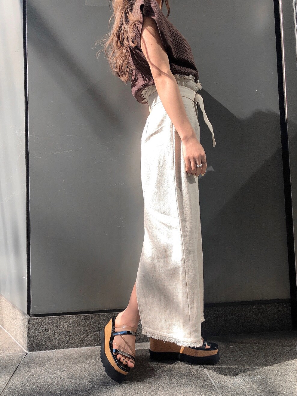 ホワイト系のスカート、ブラック系のサンダル、ブラウン系のニット/セーターを着用したレディースの春コーディネートの5枚目の写真