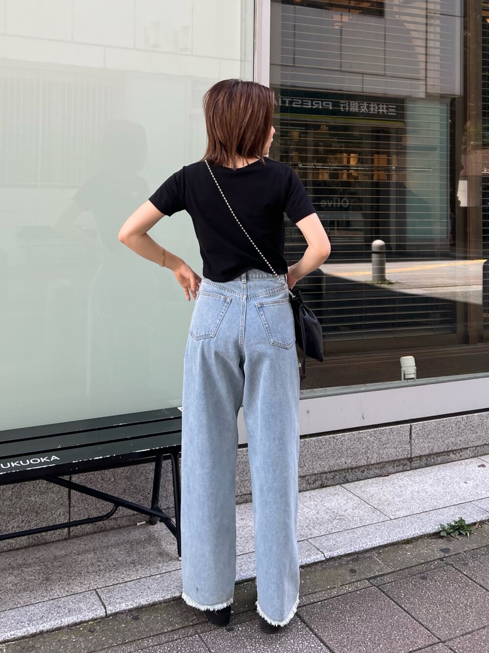 ブラック系のTシャツ/カットソー、ブルー系のデニムパンツ、ブラック系のショルダーバッグを着用したレディースの夏コーディネートの2枚目の写真