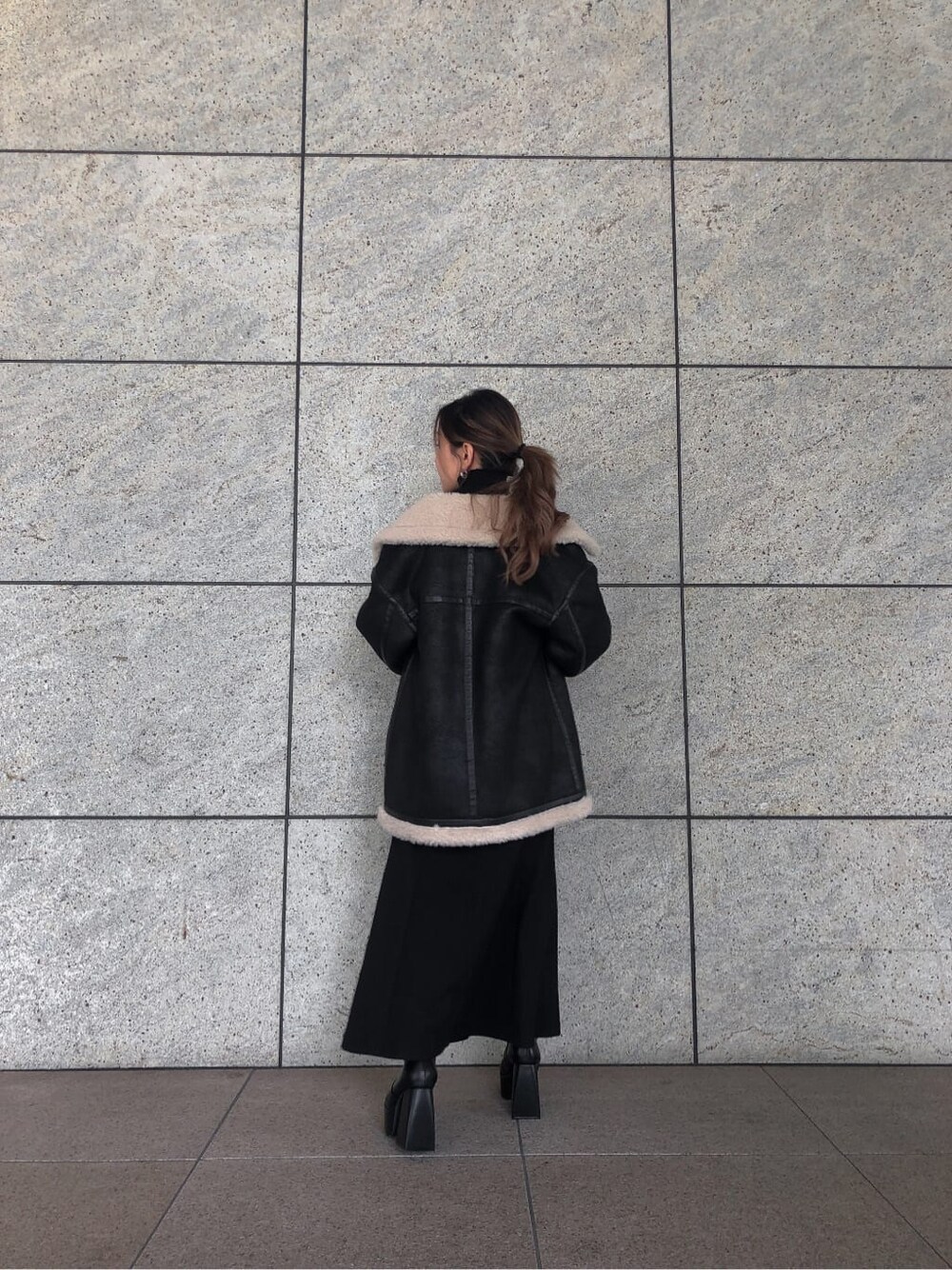 ブラック系のスカート、ブラック系のブルゾン、ブラック系のブーツを着用したレディースの秋コーディネートの5枚目の写真