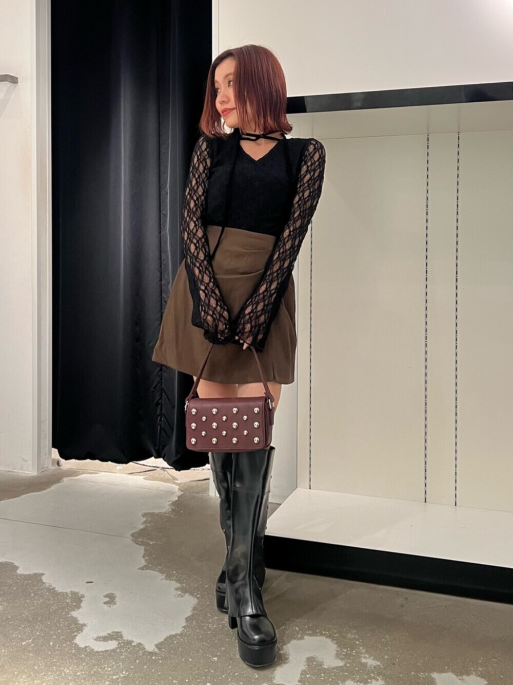 ブラック系のTシャツ/カットソー、ブラウン系のスカート、ブラック系のブーツを着用したレディースの秋コーディネートの4枚目の写真