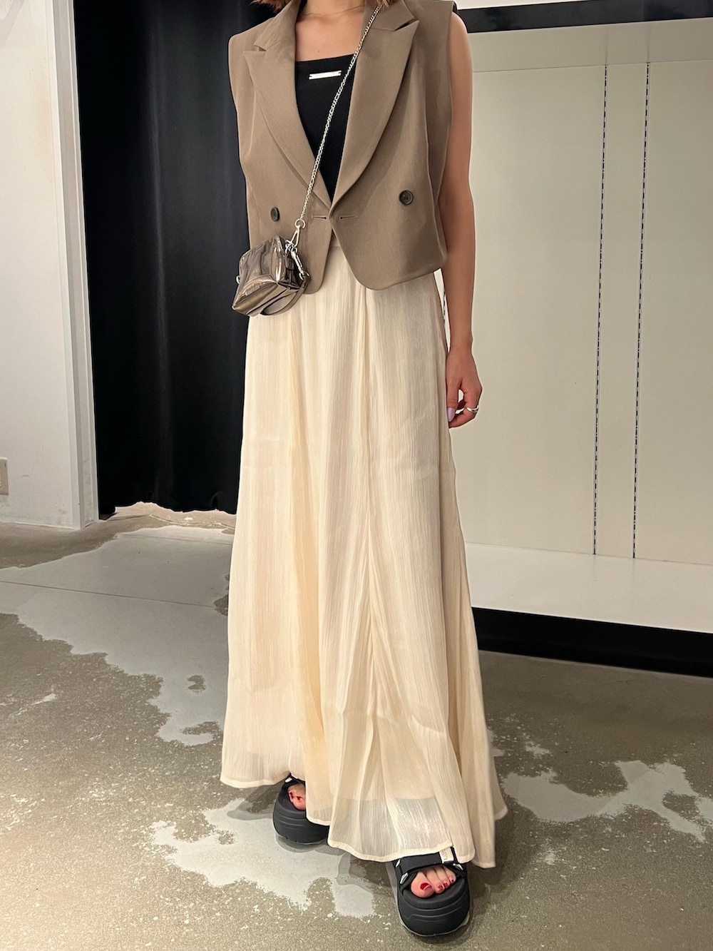 ブラック系のサンダル、ホワイト系のスカート、ゴールド系のショルダーバッグを着用したレディースの夏コーディネートの6枚目の写真