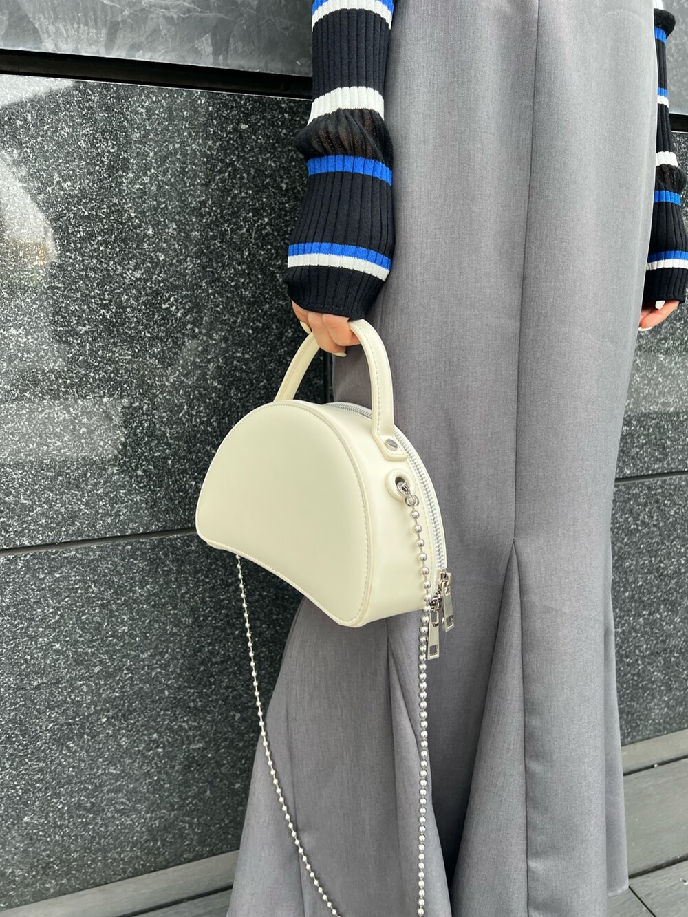 ブルー系のポロシャツ、グレー系のスカート、ブラック系のブーツを着用したレディースの春コーディネートの7枚目の写真