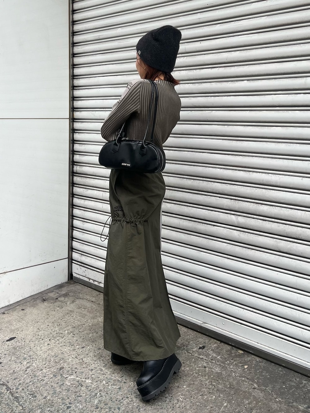 ブラック系のブーツ、グリーン系のニット/セーター、グリーン系のスカートを着用したレディースの秋コーディネートの3枚目の写真