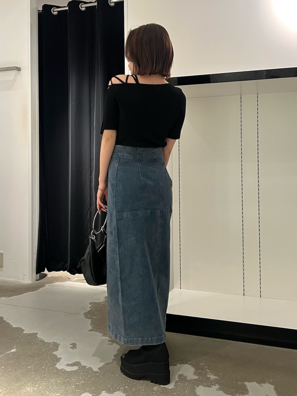 ブルー系のデニムスカート、ブラック系のニット/セーター、ブラック系のサンダルを着用したレディースの夏コーディネートの4枚目の写真