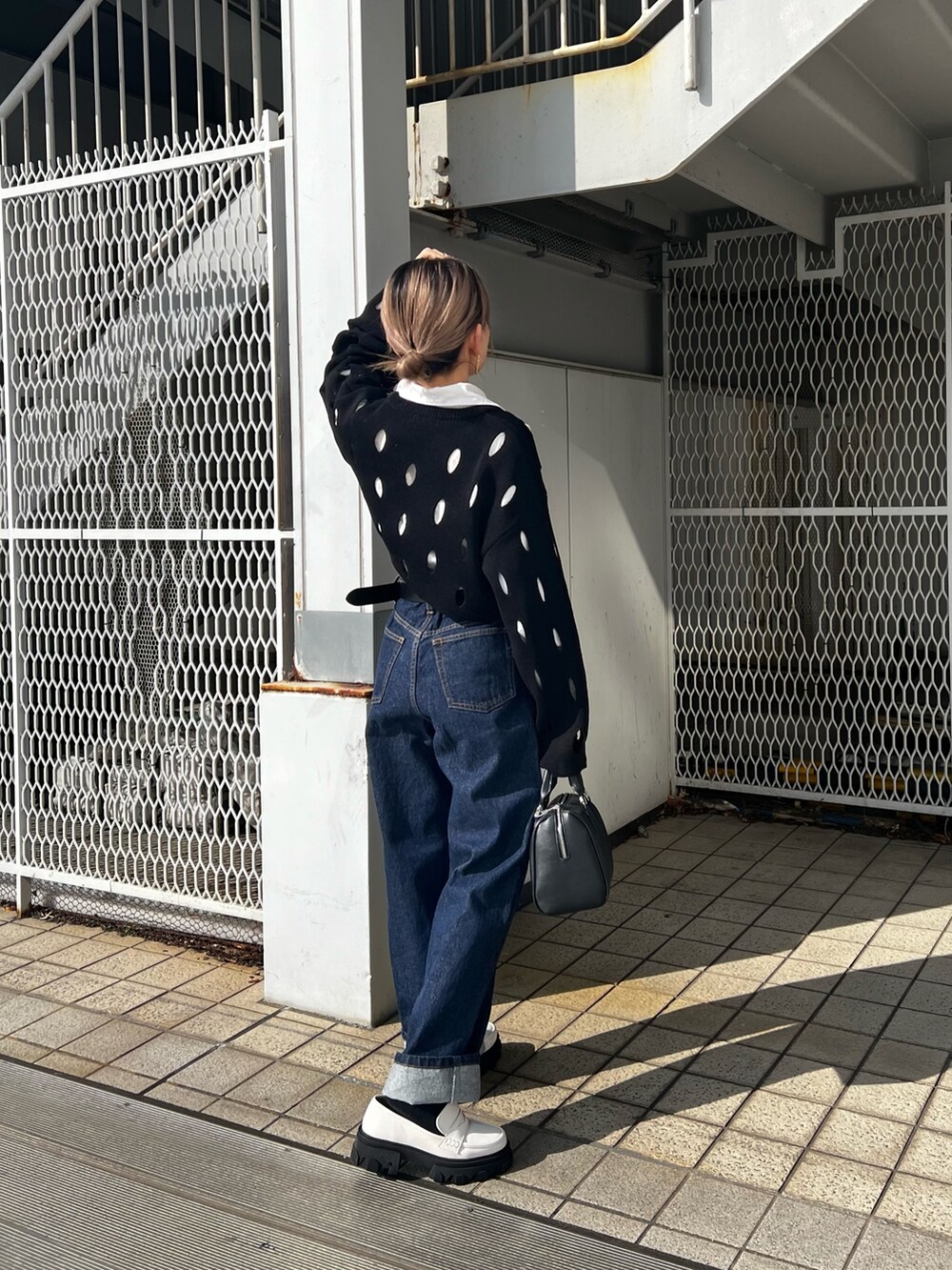ブルー系のデニムパンツ、ホワイト系のローファー、ブラック系のニット/セーターを着用したレディースの冬コーディネートの3枚目の写真