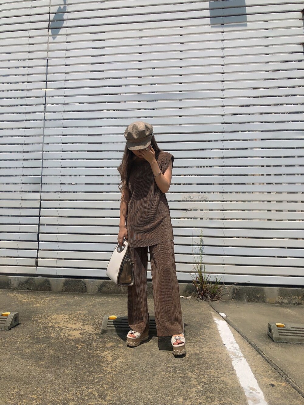 ベージュ系のシャツ/ブラウス、ブラウン系のハンドバッグ、ホワイト系のサンダルを着用したレディースの夏コーディネートの3枚目の写真