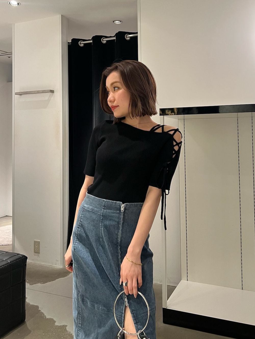 ブルー系のデニムスカート、ブラック系のニット/セーター、ブラック系のサンダルを着用したレディースの夏コーディネートの5枚目の写真